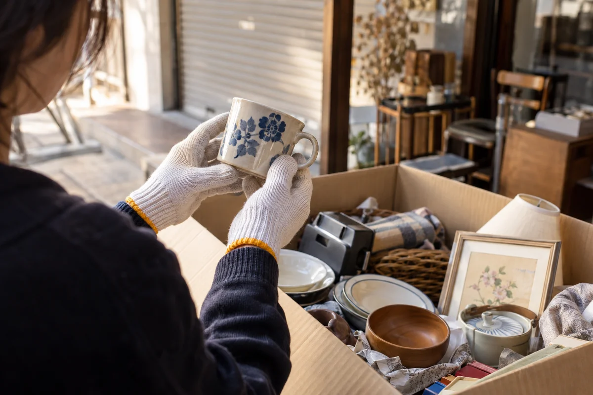 処分前に箱の中の品物を確認し、カップを手に取る様子のイメージ写真